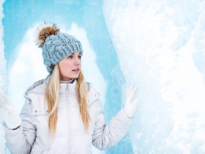 Woman in white winter coat and gray knit cap standing on snow co